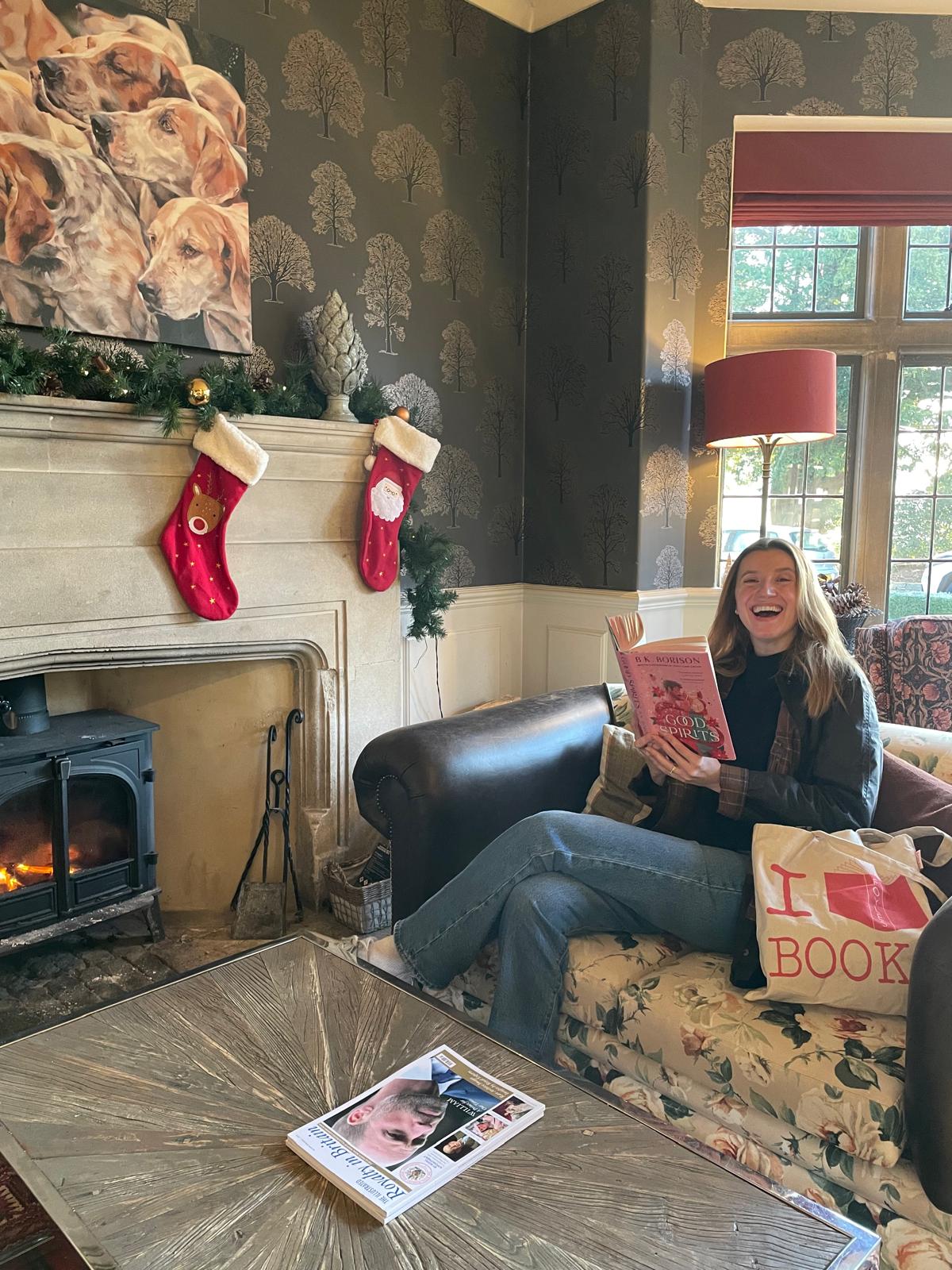 Emily reading by a fireplace, laughing