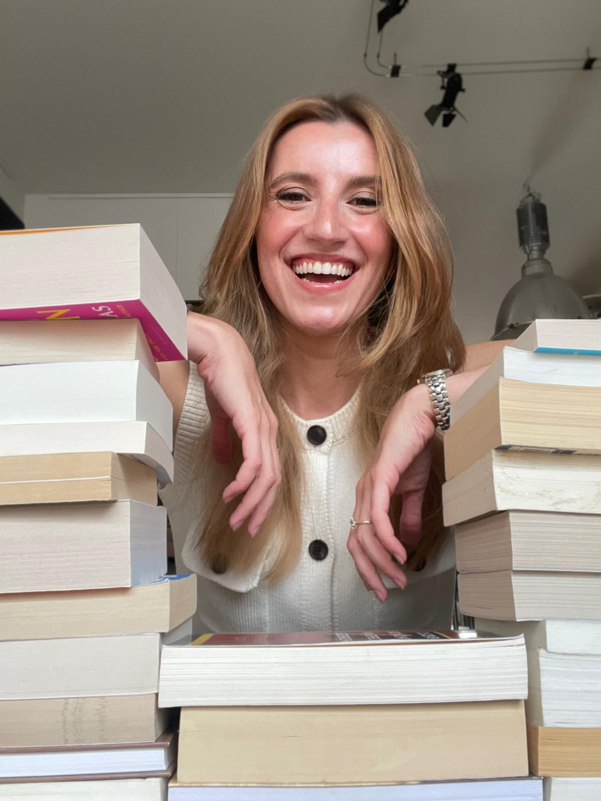 Emily laughing behind two tall stacks of books